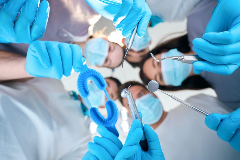 Men and women with dental instruments in their hands, people in medical uniforms and protective gloves